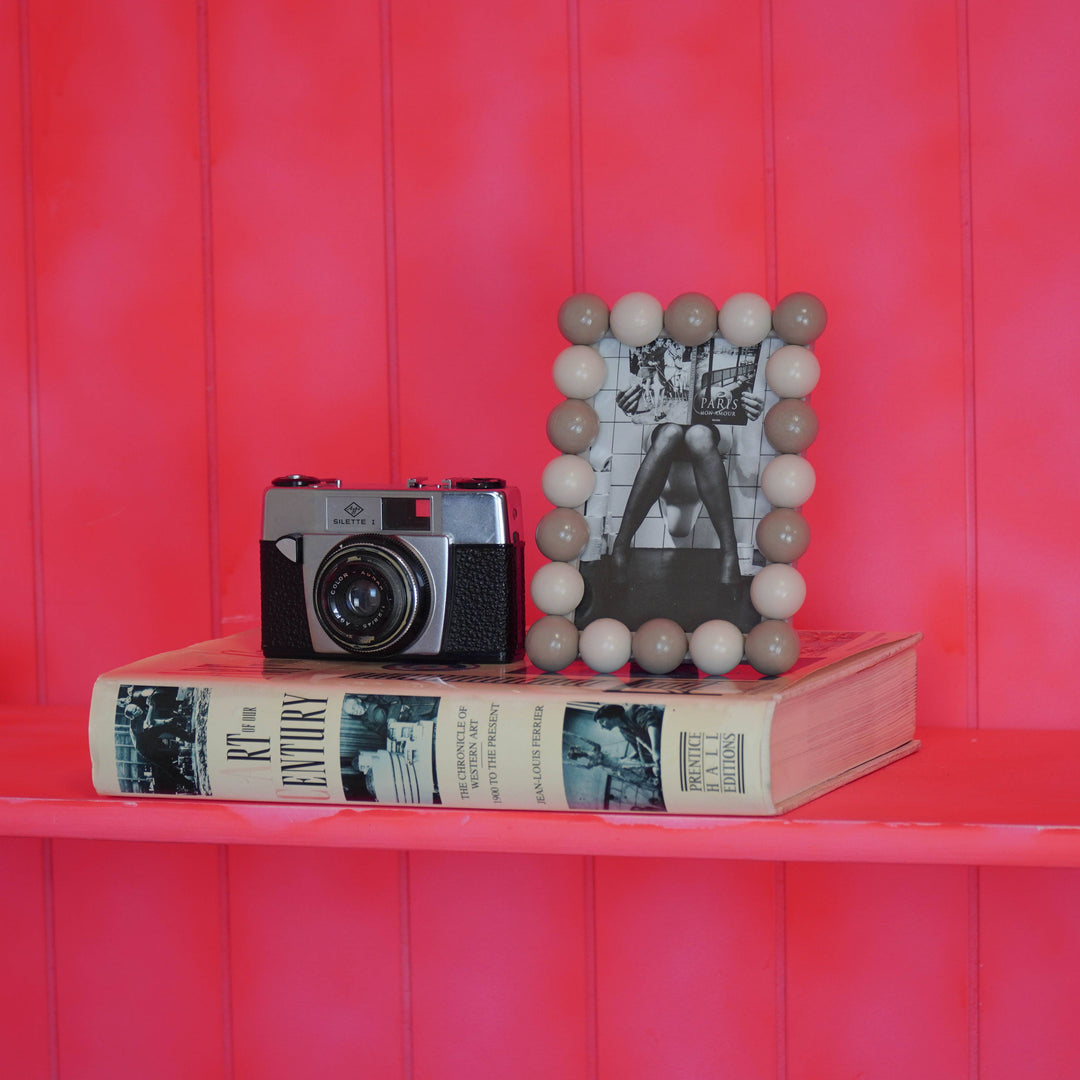 Dekorativer Bilderrahmen mit Kugelrand auf Regal