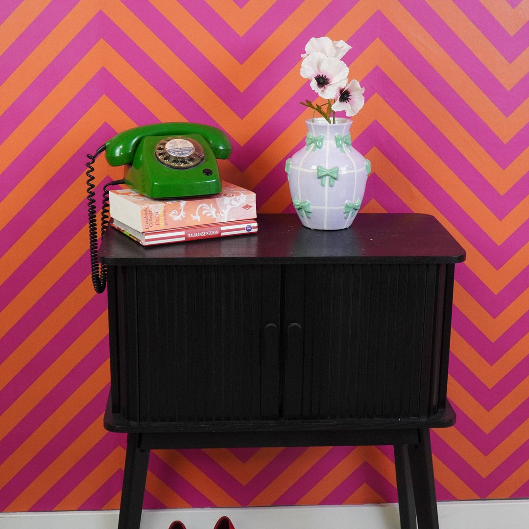 Runde Keramikvase mit Schleifendetails auf Sideboard